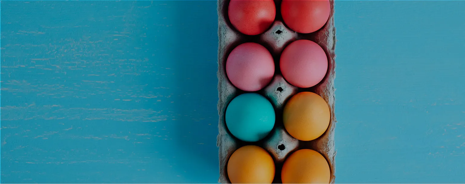 An egg carton with coloured eggs on a blue background